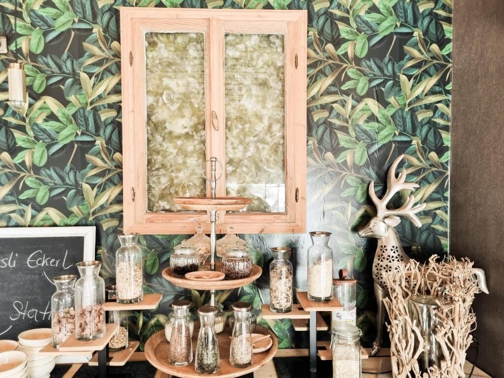 A room with a wooden cabinet, shelves with jars, and a chalkboard sign.