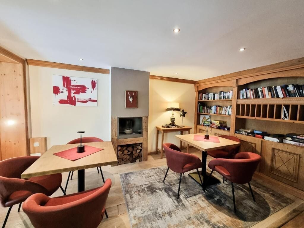 A cozy room with a fireplace, bookshelves, and two tables with chairs.