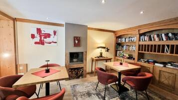 A cozy room with a fireplace, bookshelves, and two tables with chairs.