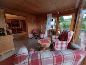 Un interior acogedor de madera con mobiliario escocés, una chimenea y vistas al exterior.
