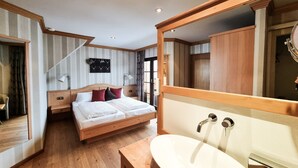 Un dormitorio con una cama de madera, un espejo grande, un lavamanos blanco y un suelo de madera.