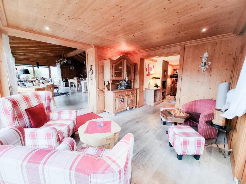 A cozy room with a wooden ceiling, a sofa set, a small round table, and a chess table.
