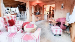 Una habitación acogedora con techo de madera, un conjunto de sofás, una mesita redonda y una mesa de juego de ajedrez.