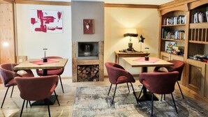 Un comedor con chimenea, estanterías y sillas rojas.