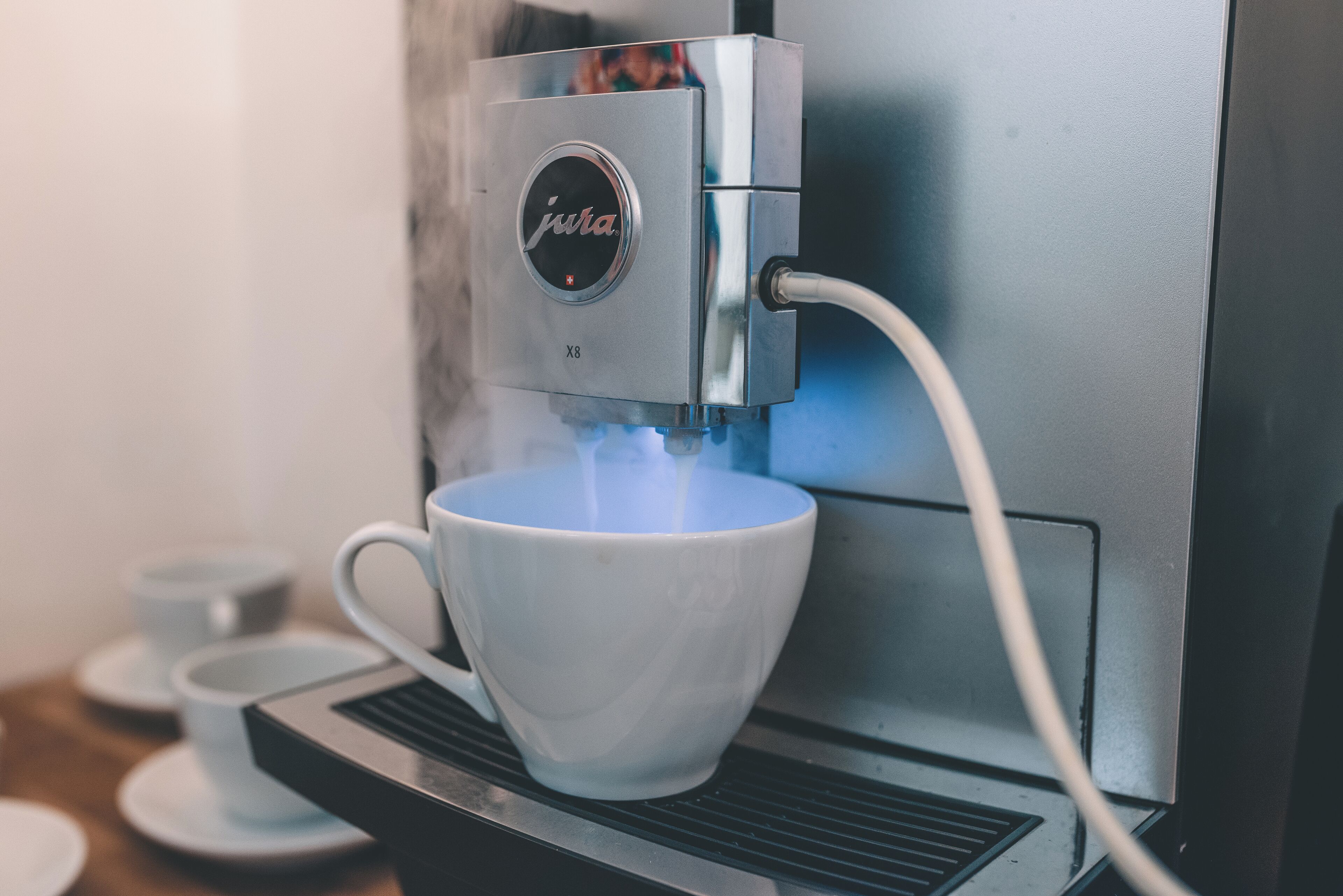 A coffee machine with a cup placed underneath it, steam rising from the cup.