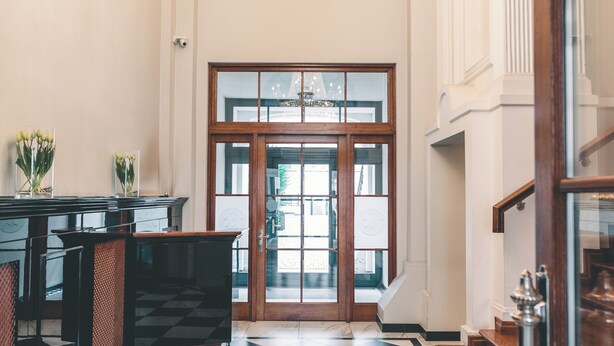 A lobby with a checkered floor, a chandelier, a reception desk, and a staircase. - Fortune Boutique Old Town (Poznan)