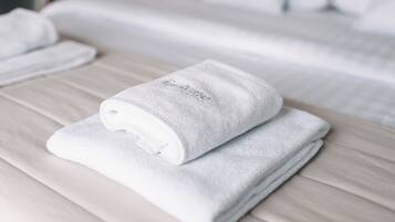 Een keurig opgevouwen witte handdoek op een bed met een houten hoofdeinde.