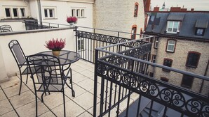 A balcony with a table and chairs, a potted plant, and a decorative railing. - Fortune Boutique Old Town (Poznan)