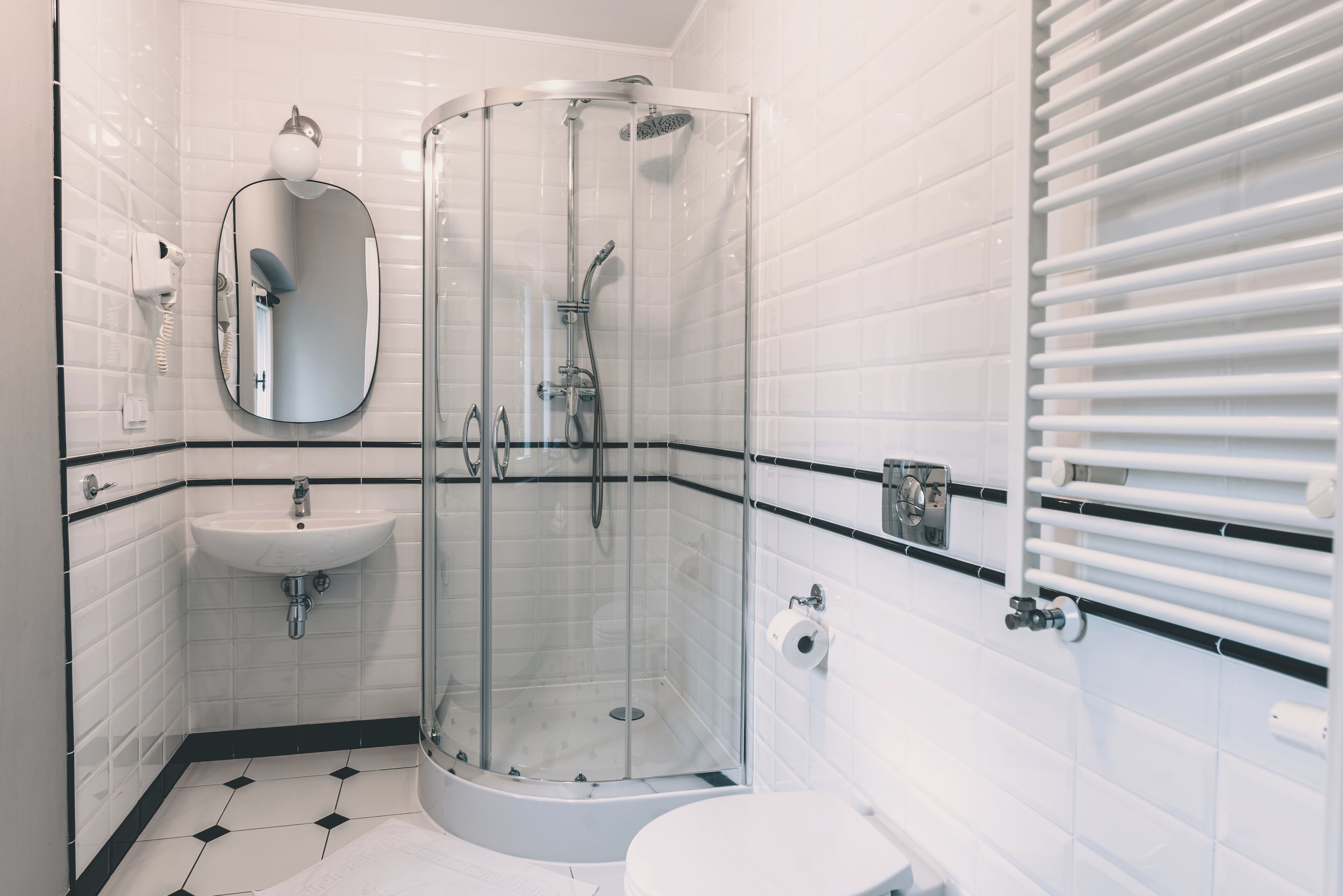 A bathroom with a glass-enclosed shower, a sink, a toilet, and a mirror.