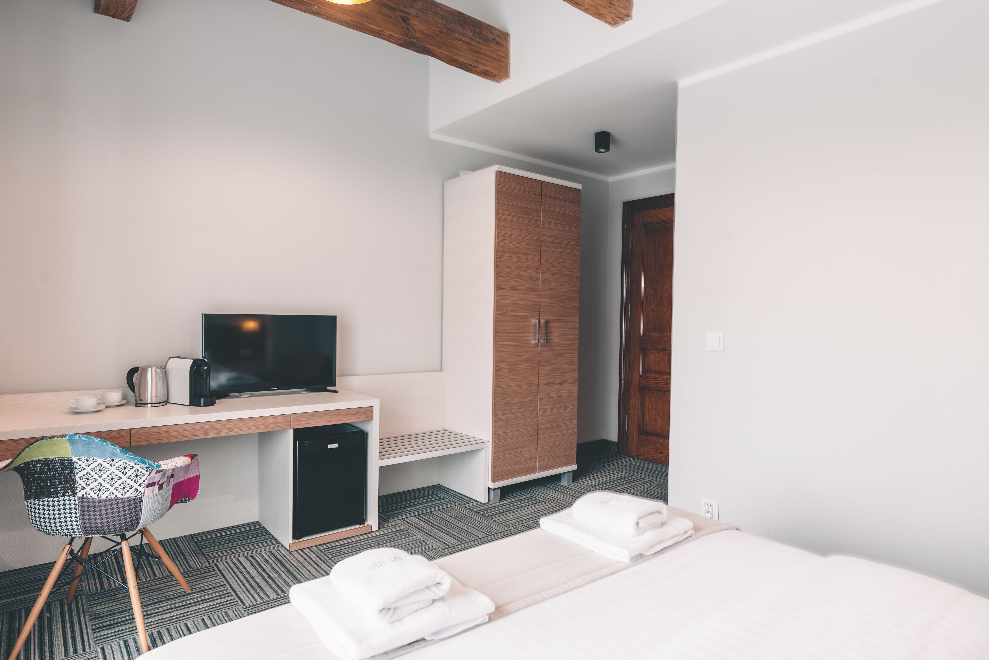 Une chambre d’hôtel comprenant un lit, un bureau avec un ordinateur, une télévision et une armoire.