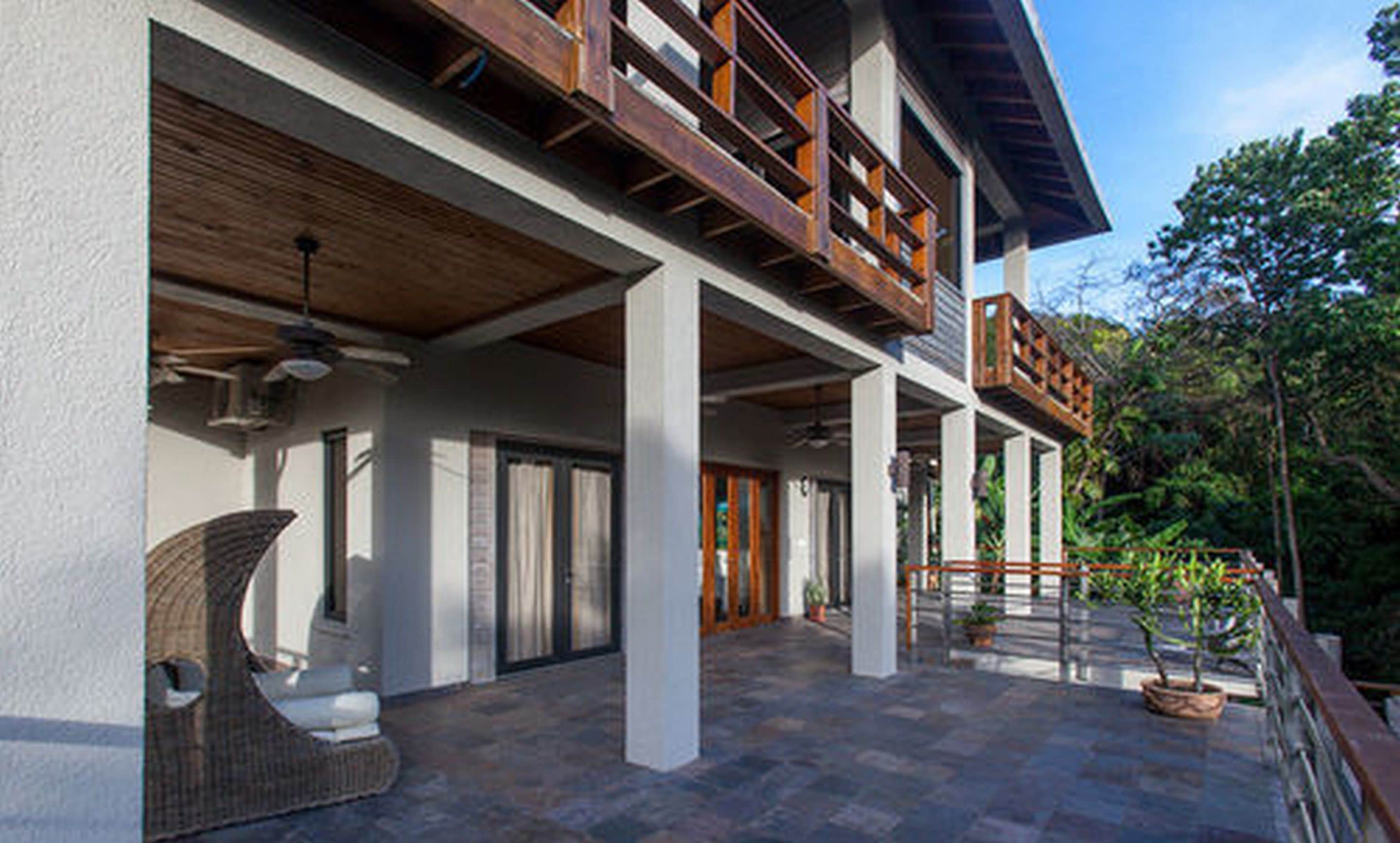 A modern building with a spacious patio area, large windows, and a wooden balcony.
