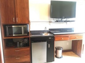 A compact kitchen with a microwave, stove, sink, and dishwasher.