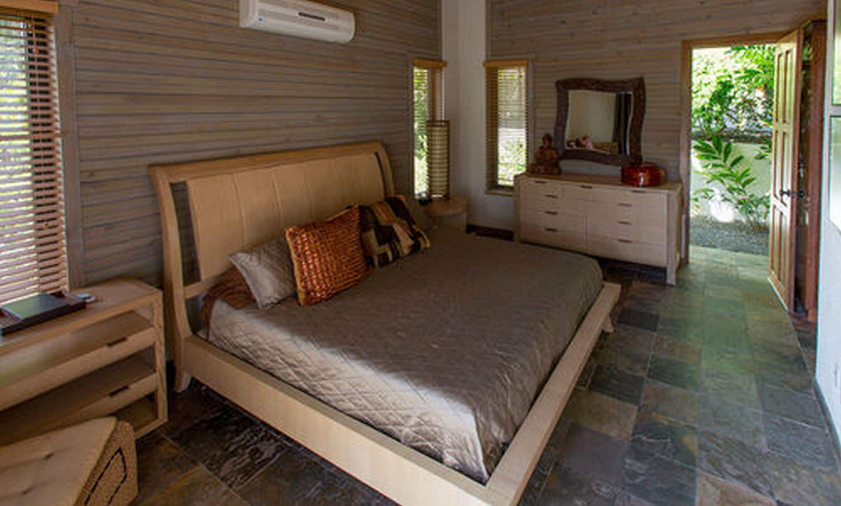 Una camera da letto con un letto grande, comodini in legno, una cassettiera e uno specchio.