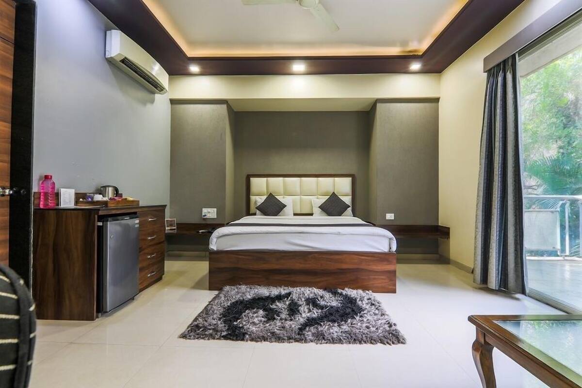 Un dormitorio con cama, mesitas de noche, un escritorio y una ventana.