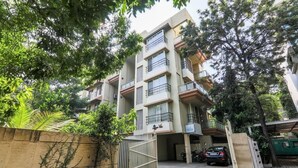 Un immeuble résidentiel à plusieurs étages, doté de balcons, d’une entrée sécurisée et d’un espace de stationnement.