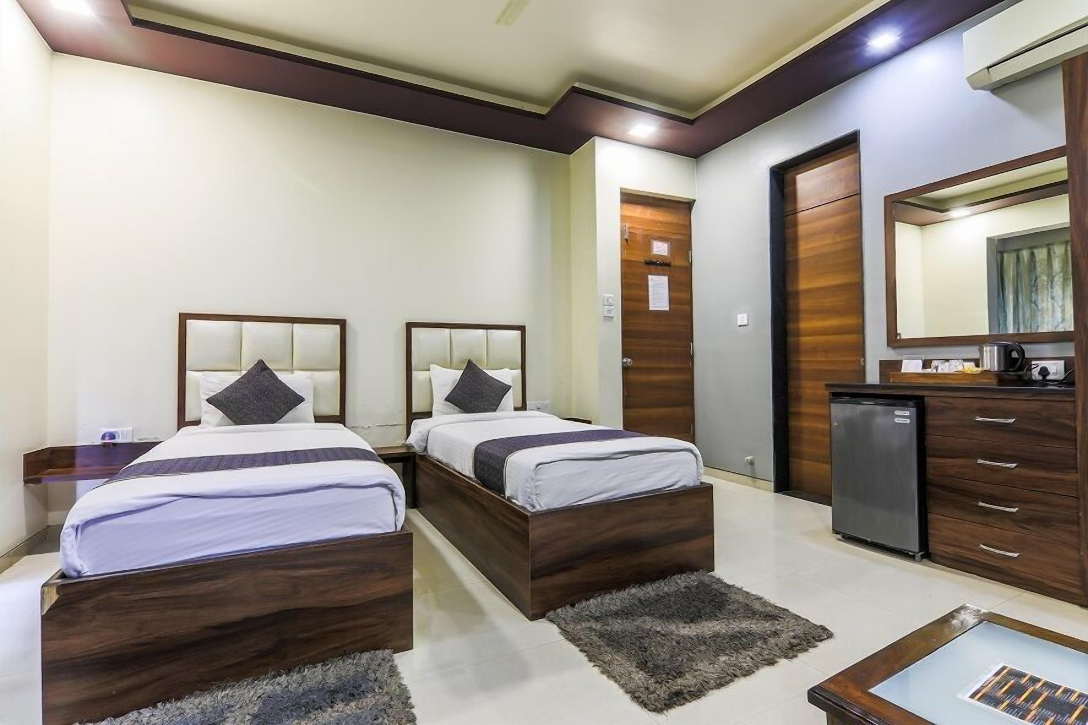 Habitación de hotel con dos camas, una kitchenette pequeña, un espejo y un baño compacto.