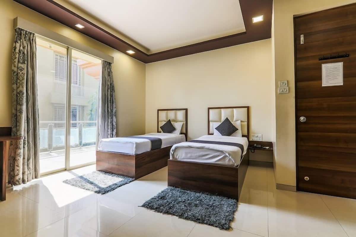 Una habitación de hotel con dos camas, una puerta corrediza de vidrio al exterior y una puerta de madera.