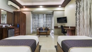 Une chambre d’hôtel avec deux lits, un bureau, une télévision et une armoire.