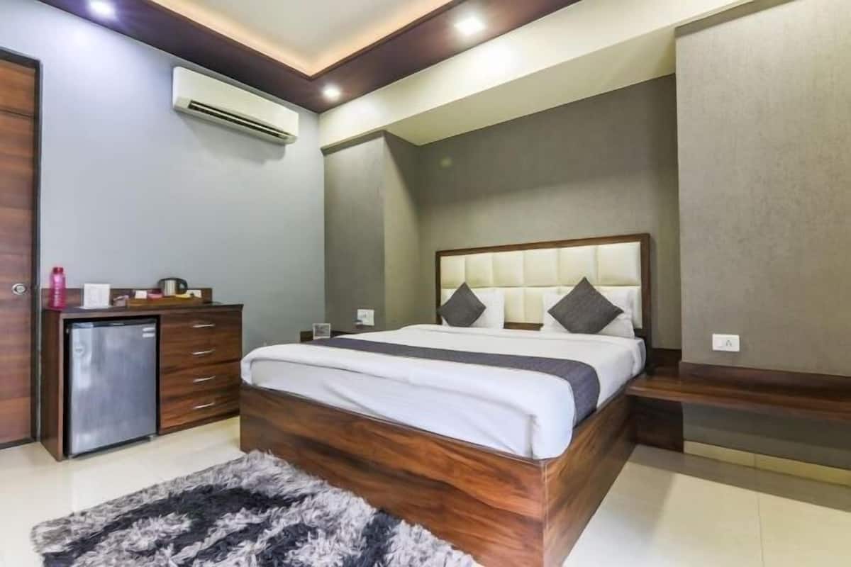 Un dormitorio con cama, cómoda y un refrigerador pequeño.
