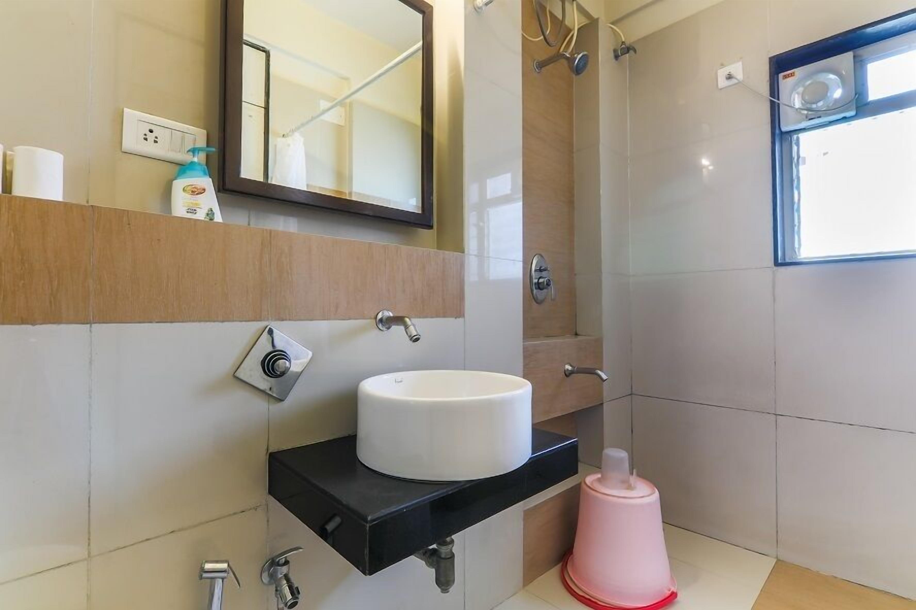 A modern bathroom with a white sink, black countertop, and a mirror above it.