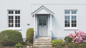 A two-story building with a white facade, a front door with a small porch, and a set of stone steps leading to the entrance. - Rose & Crown (Plymouth)