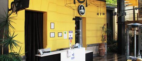 Un espace d’accueil comprenant un comptoir, un panneau indicateur et une plante.