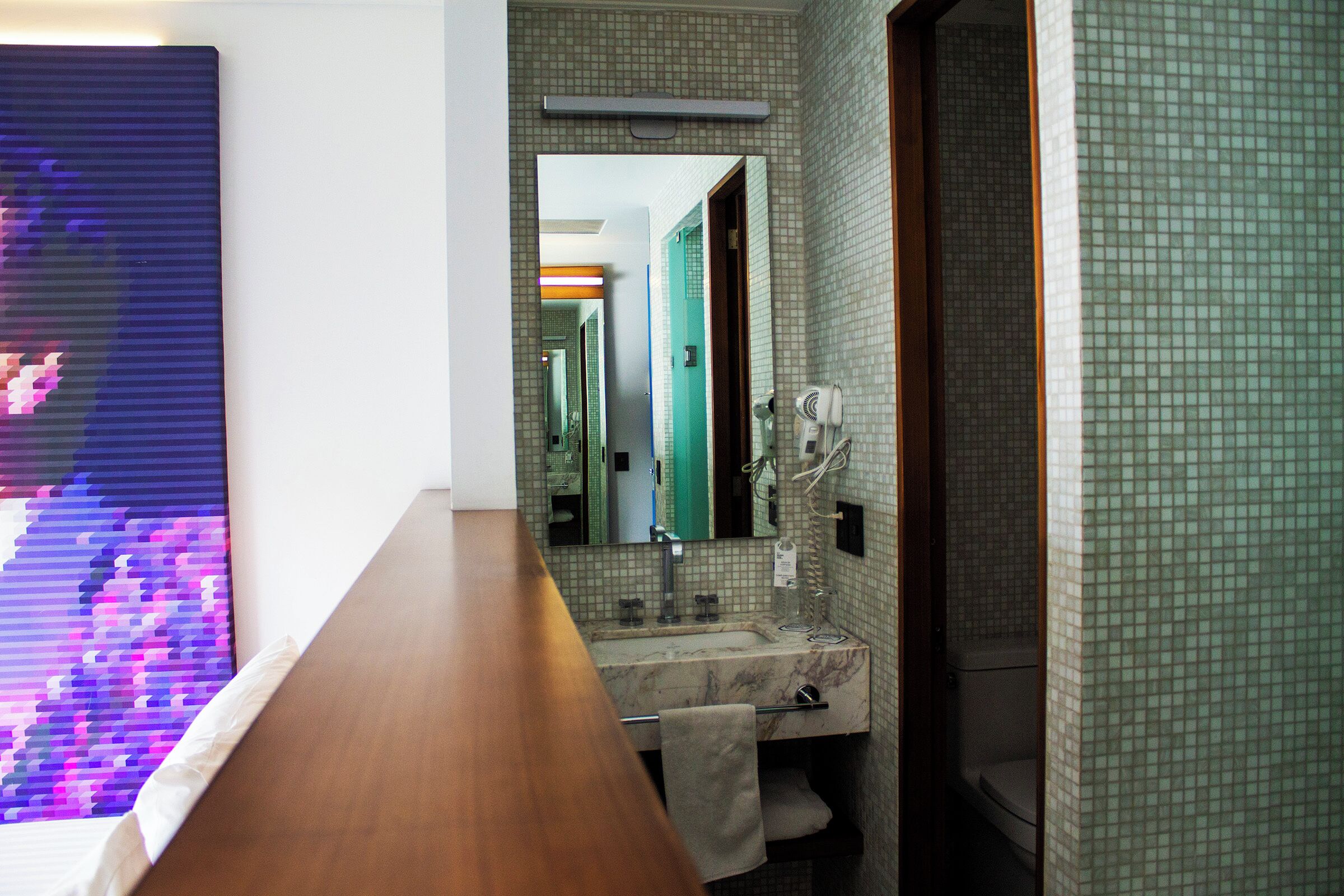 A bathroom with a marble sink, a mirror, and a towel rack.