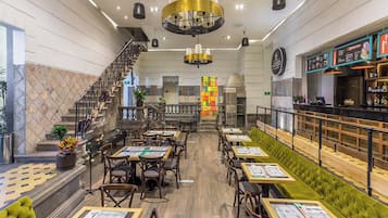 A restaurant with a bar area, multiple seating options including booths and tables, and a staircase leading to an upper level.