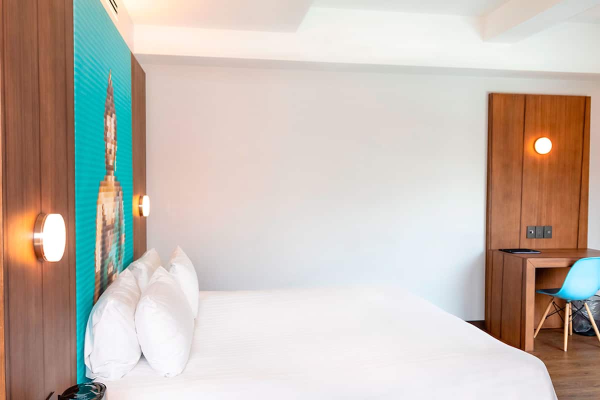 A hotel room with a bed, a desk, and a chair.