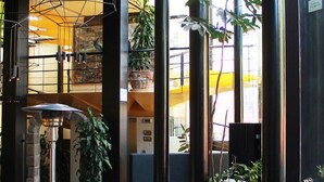 Un vestíbulo moderno con un sofá amarillo curvo, ventanas amplias y plantas de interior.
