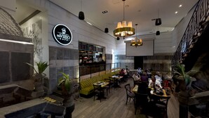 Una cafetería con pared de piedra, asientos verdes y una barra.