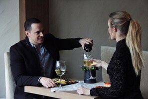 Una mesa de comedor con dos personas sentadas, una sirviendo vino en una copa.