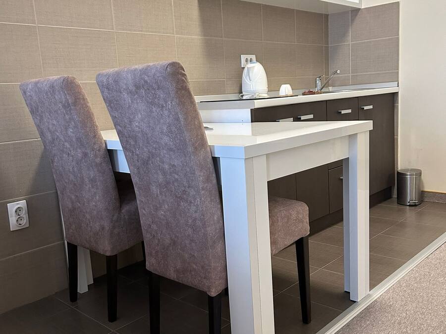 A small kitchenette with a white countertop, two chairs, a sink, and a mirror above the counter.
