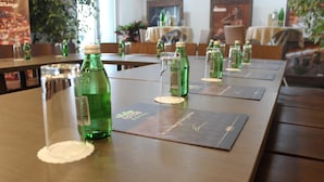 Een restaurantsetting met gedekte tafels, met groene flessen en glazen op placemats.
