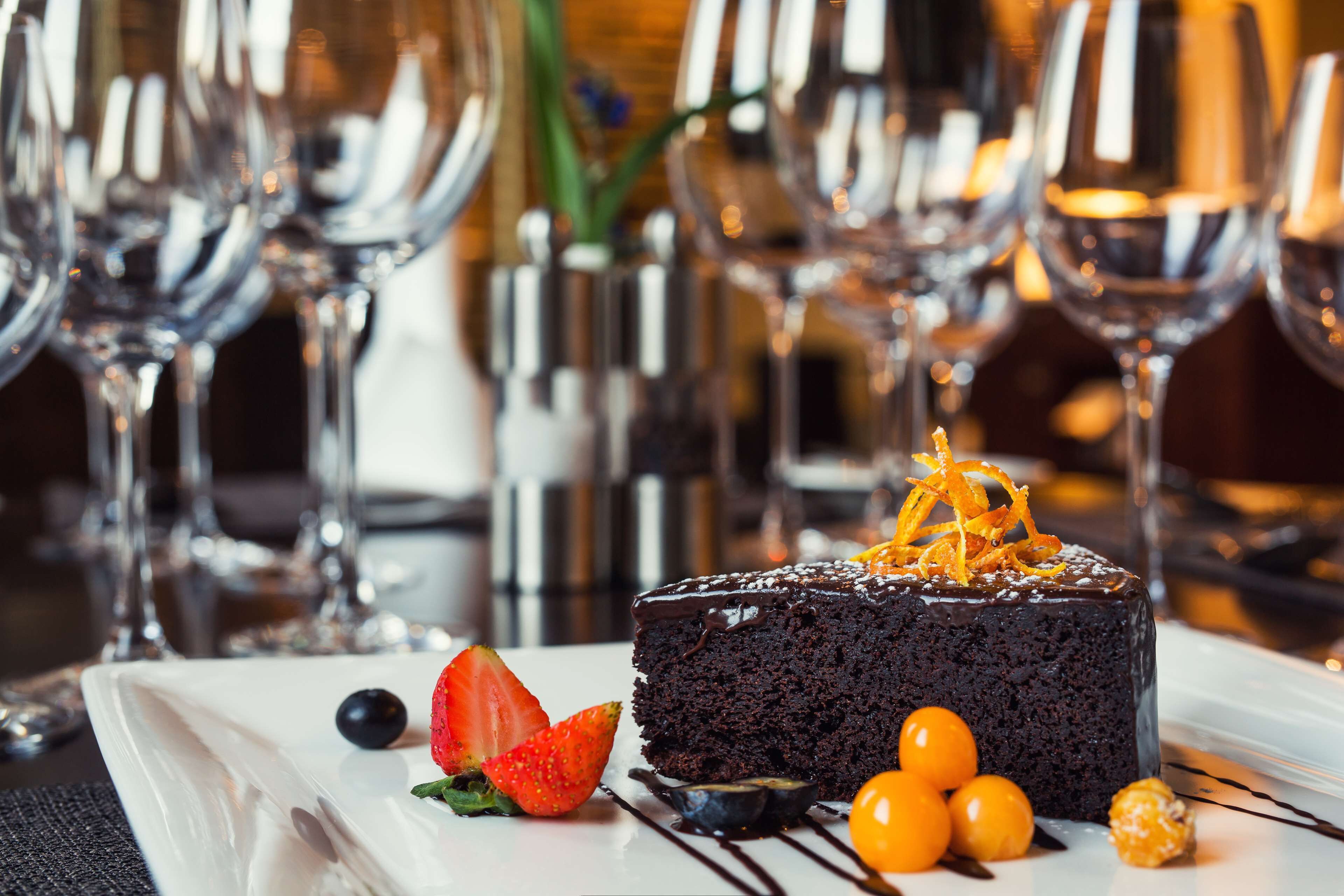 A chocolate cake with strawberries and cherries on a white plate.