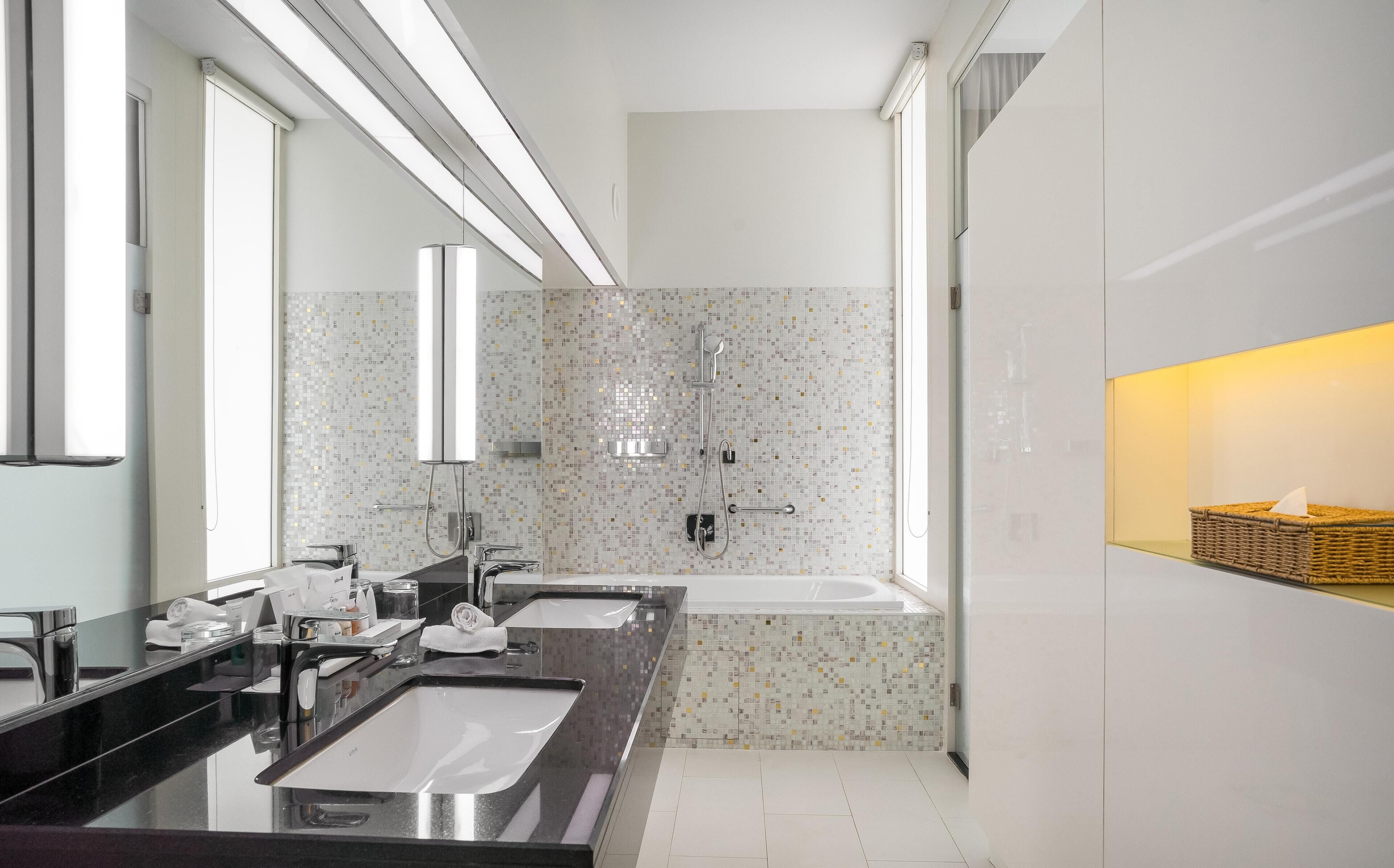 Een moderne badkamer met twee wasbakken, een douche en een grote spiegel.