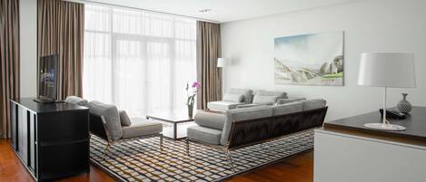 Una habitación de hotel moderna con un sofá, un escritorio, un televisor y un cuadro en la pared.