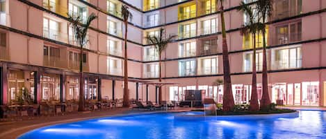 Un hôtel à plusieurs étages doté d’une piscine centrale, de balcons et d’espaces de détente en plein air.