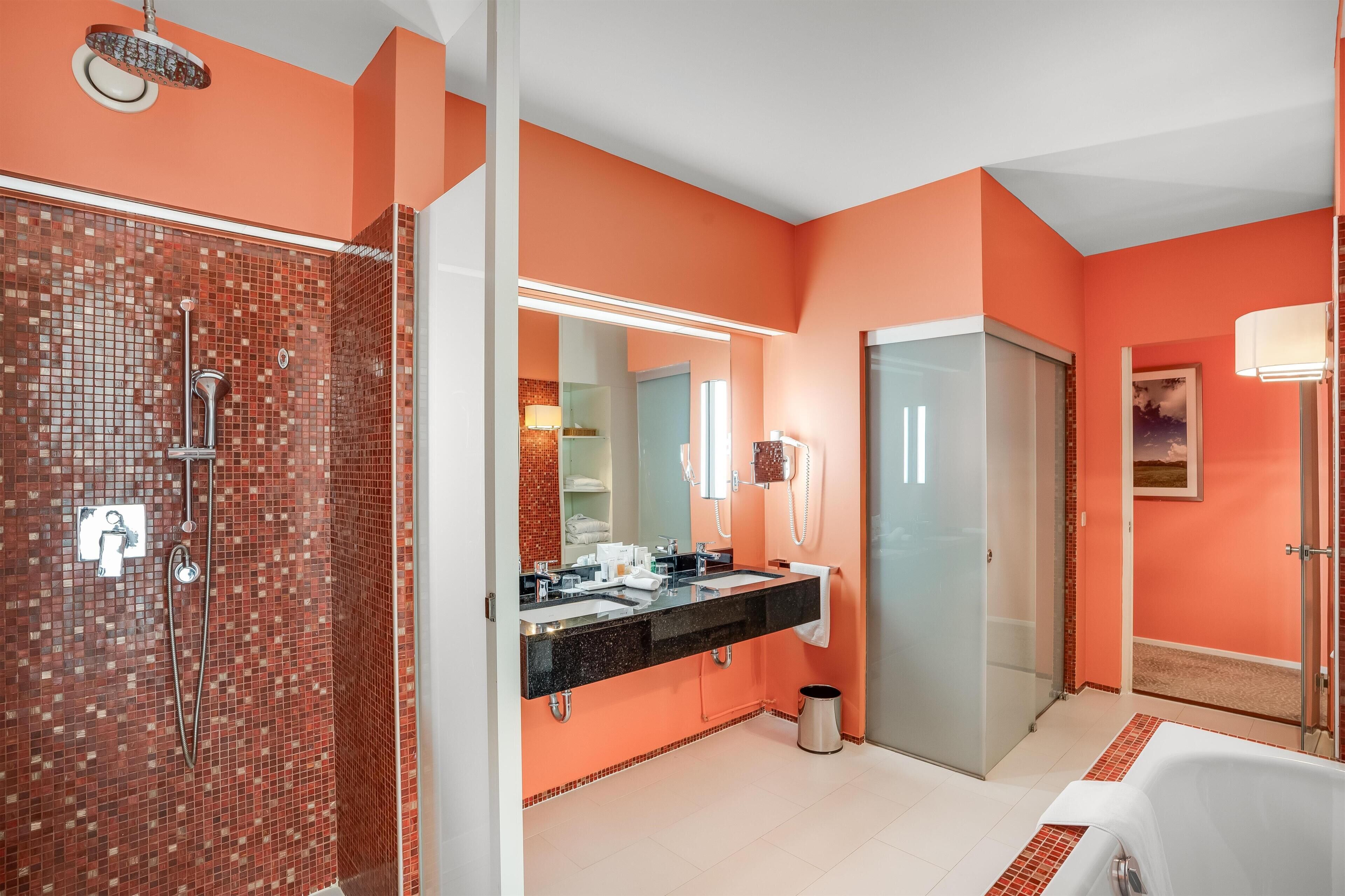 A modern bathroom with a tiled shower, a double sink vanity, and a large mirror.
