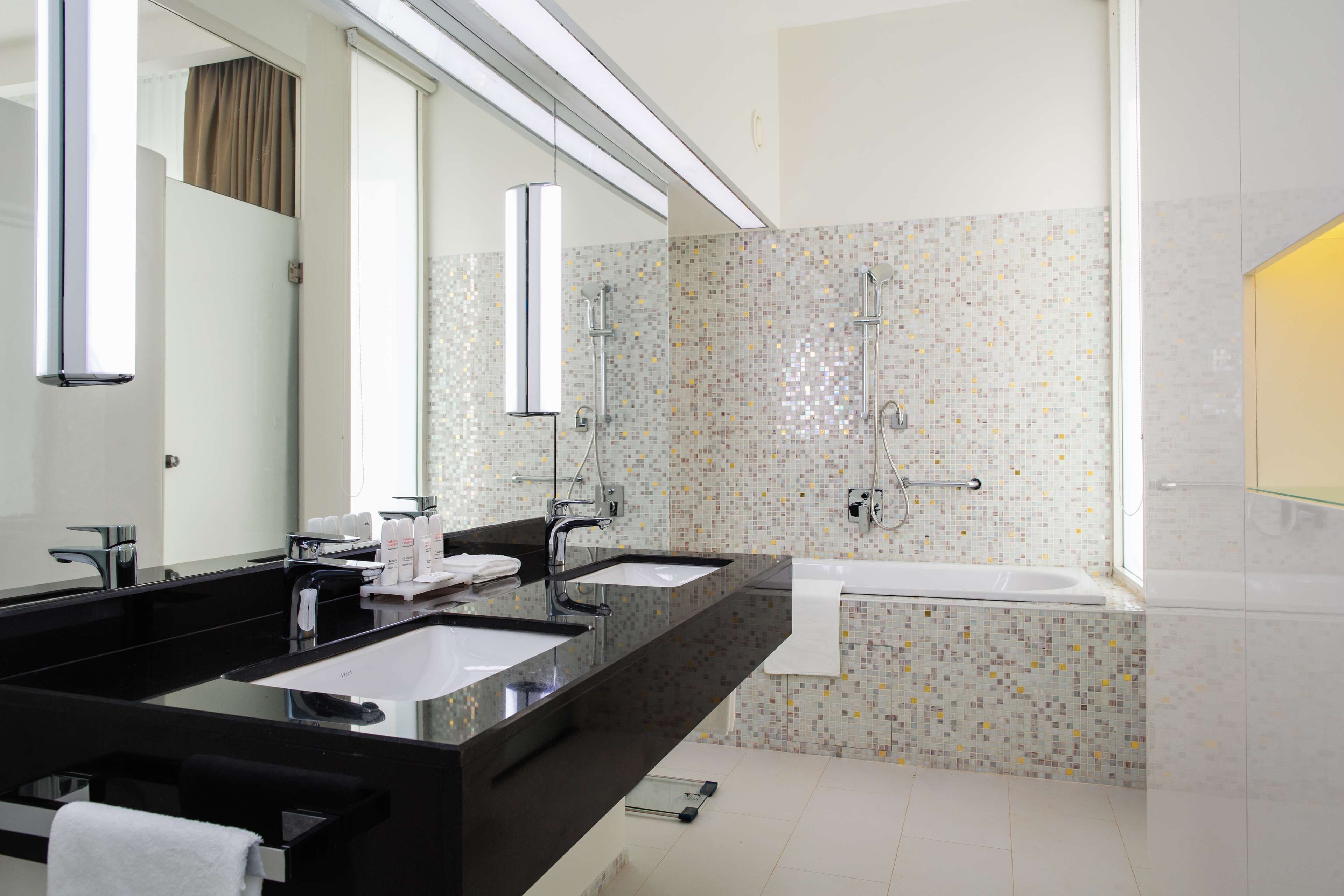 Une salle de bain moderne avec deux lavabos, un grand miroir, une douche et une baignoire.