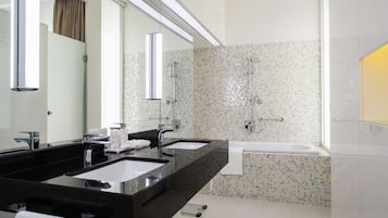 Une salle de bain moderne avec deux lavabos, un grand miroir, une douche et une baignoire.