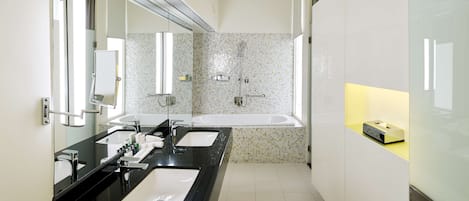 A modern bathroom with two sinks, a large mirror, a bathtub, and a vanity with a soap dispenser.