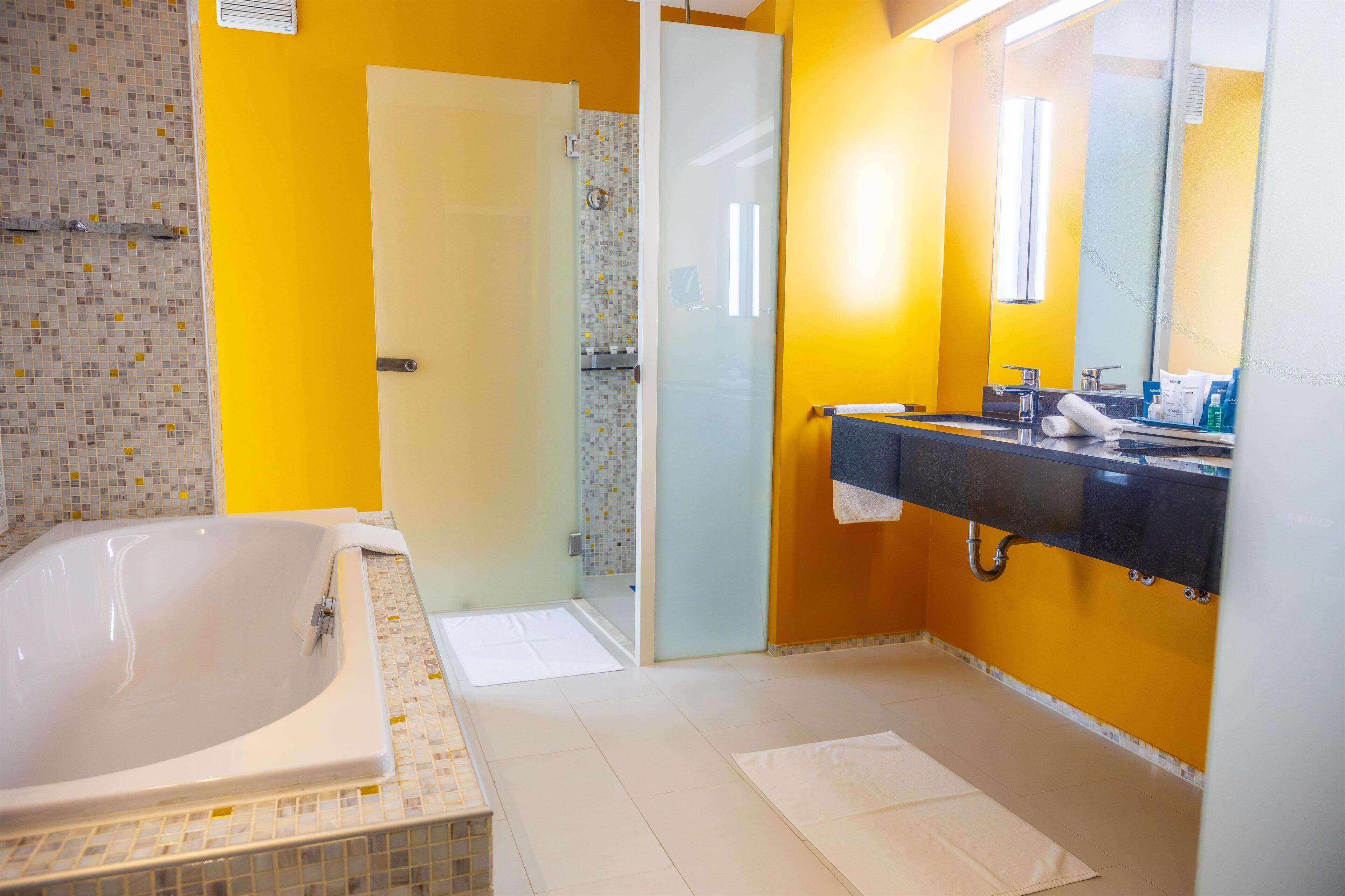 A bathroom with a bathtub, a shower, and a sink with a mirror.