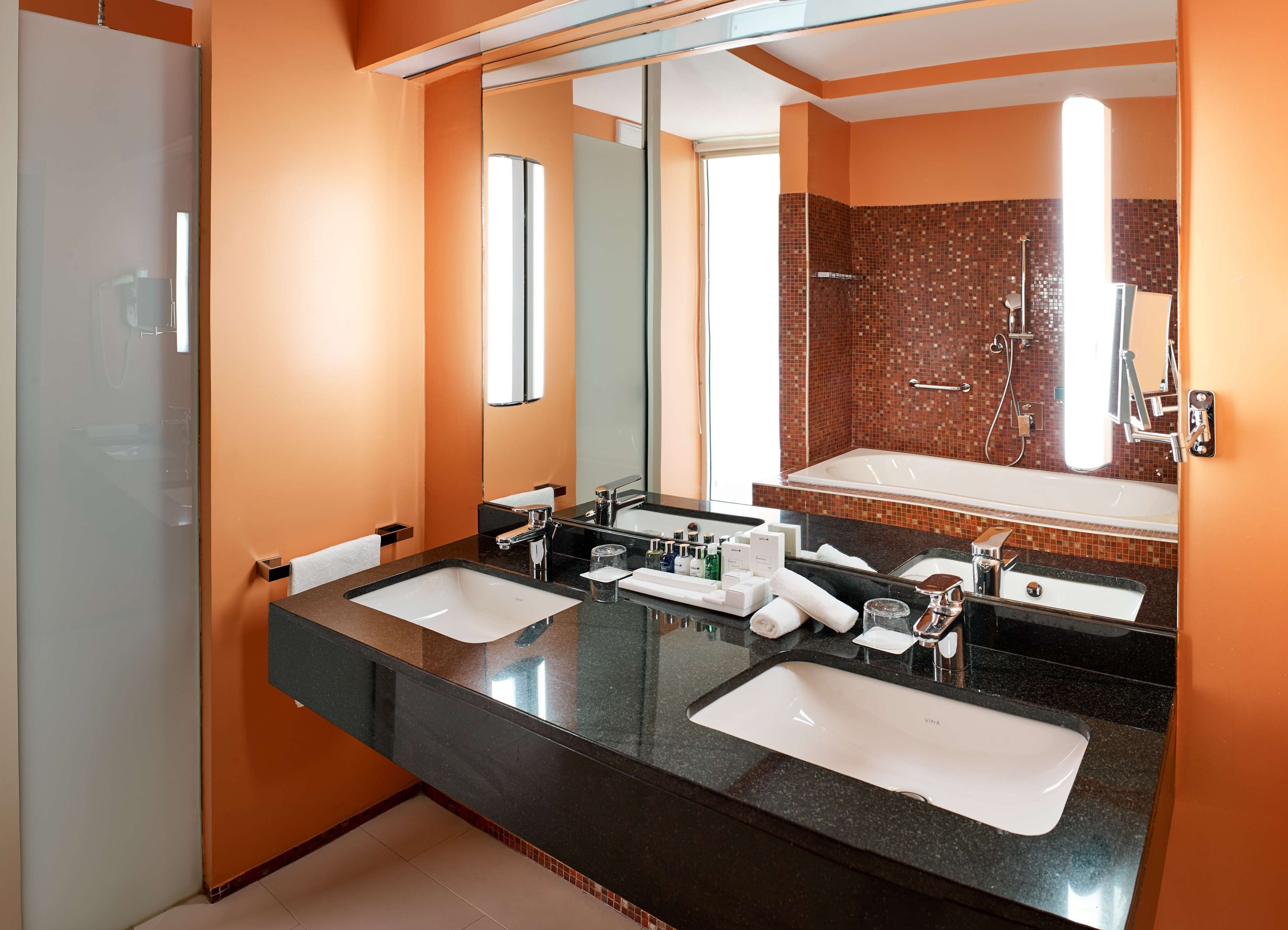 Un baño moderno con dos lavamanos, un espejo grande y una bañera.
