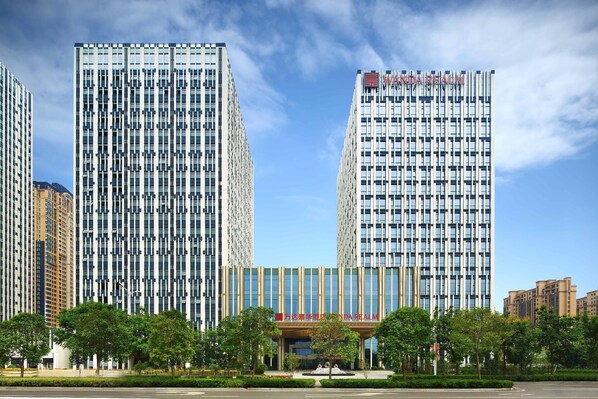 A modern building with a prominent sign, surrounded by trees and other buildings.