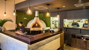 Um restaurante com balcão de tijolos, luminárias pendentes e forno a lenha.