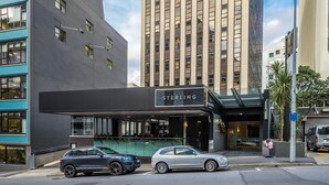Um edifício moderno com uma placa de destaque 'STERLING', fachada de vidro e área de estacionamento com carros.