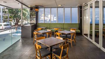 A restaurant with outdoor seating, including tables and chairs, and a view of the sea.