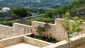 A stone wall with a garden area, including red flowers and green shrubs. - Lagoon View Apartments - Adults Only (Kefalonia)