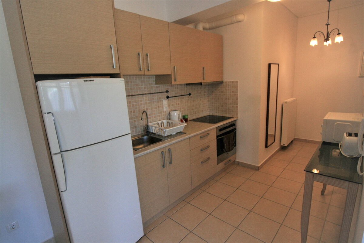 A kitchen with light wooden cabinets, a white refrigerator, a sink, and a stove.